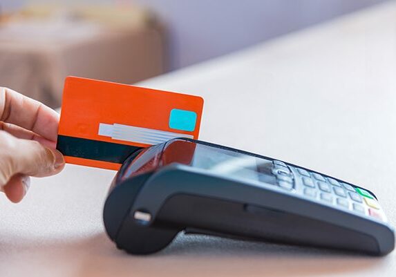 Hand Swiping Credit Card on POS terminal in Store.